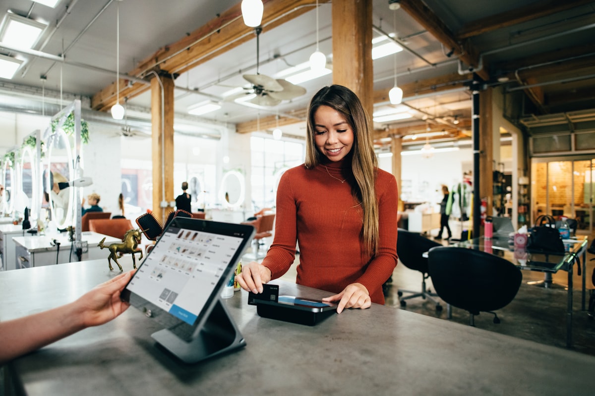 A retail worker completing a contactless payment at a point-of-sale terminal